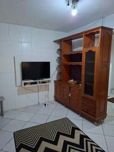 a living room with a tv and a wooden cabinet at Meu Aconchego in Embu