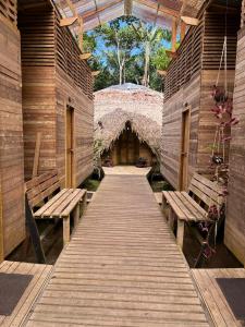 a wooden walkway with benches and a thatched building at Palmayacu - Refugio Amazónico in Leticia