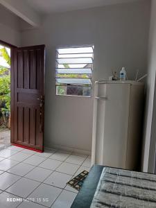 a kitchen with a refrigerator and a window and a door at LAR DE PRAIA - Suíte in Serra