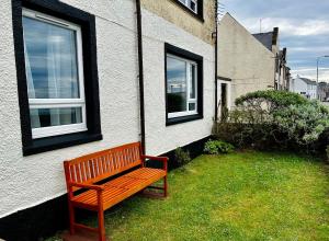 a wooden bench sitting next to a building at Newton Marina View in Stornoway