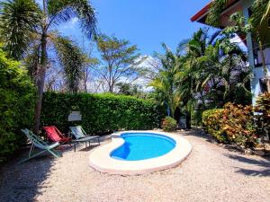 a small swimming pool in a yard with two chairs at Casa Ceiba Samara in Sámara