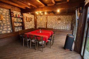a dining room with a red table and chairs at Къща за Гости Тодор in Shiroki Dol