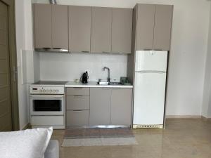 a kitchen with white cabinets and a white refrigerator at Anna Coast Apartment in Agia Anna +5 photos