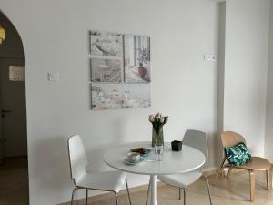 a white dining room with a white table and chairs at Anna Coast Apartment in Agia Anna