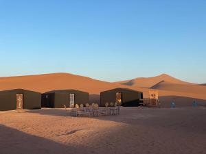 a group of tents in the middle of a desert at Tarrast Desert Camp in Mhamid