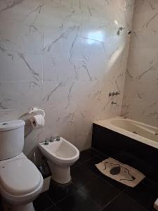 a bathroom with a toilet and a sink and a tub at Nuestro refugio in Roldán