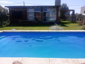 a blue swimming pool with a house in the background at Nuestro refugio in Roldán +3 photos