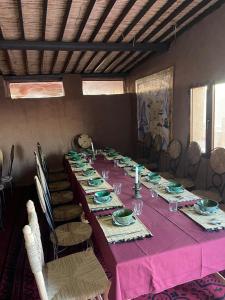 a long table in a room with a pink table cloth at Tarrast Desert Camp in Mhamid