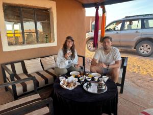 a man and a woman sitting at a table at Bivouac La Dune Blanche in Mhamid