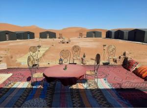 a group of chairs and a table in the desert at Tarrast Desert Camp in Mhamid