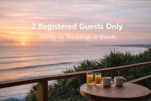 a table with two glasses of beer on it with the ocean at Oceanfront luxury apartment with views, king bed & private balcony in Coolum Beach