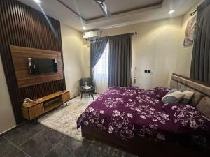 a bedroom with a purple bed and a television at Afia Cottage Inn in Ayaso