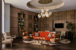 a living room with an orange couch and chairs at The Tess, Autograph Collection in Atlanta