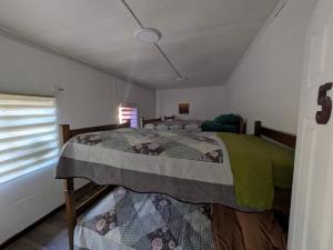 a bedroom with a bed with a quilt on it at Hostel INK - Duerme Como En Casa in Concepción