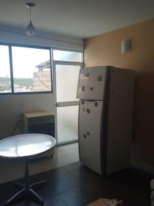 a kitchen with a refrigerator and a table and a window at SUITE CUMBAYA Junto Reservorio in Quito