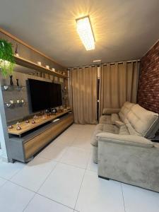 a living room with a couch and a flat screen tv at Lindo apartamento todo equipado in Criciúma