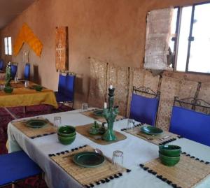 ein Esszimmer mit zwei Tischen und grünen Tellern in der Unterkunft Excursion Erg chegaga in M’hamid El Ghizlane
