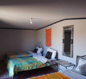 ein Schlafzimmer mit zwei Betten und einem Spiegel in der Unterkunft Excursion Erg chegaga in M’hamid El Ghizlane