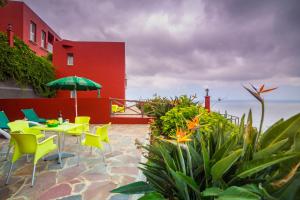 a patio with yellow chairs and a table with an umbrella at Viviendas Vacacionales Jardín La Punta in Hermigua
