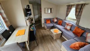 a living room with a blue couch and orange pillows at Great Yarmouth 10 Berth KP Holiday Home - NOW with Linen in Corton