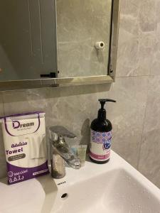 a bathroom sink with a bottle of soap and a mirror at Condo in Alramal near to the airport in Riyadh