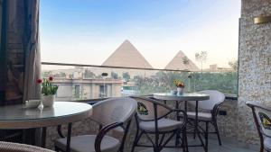 a balcony with tables and chairs and a view of the pyramids at Queen Inn Pyramids View in Cairo