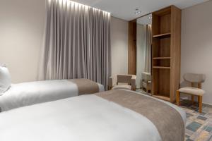 a hotel room with two beds and a chair at فندق آفال AVAL Hotel in Medina