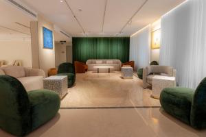a waiting room with couches and chairs and a green wall at فندق آفال AVAL Hotel in Medina