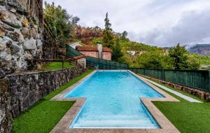 a swimming pool in front of a stone building at Casa do Monte Sereno in Celorico de Basto