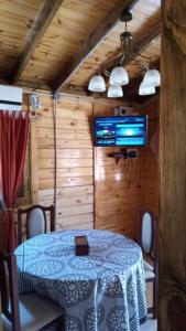 a dining room with a table and a television in a cabin at Cabaña El Refugio in La Carrera
