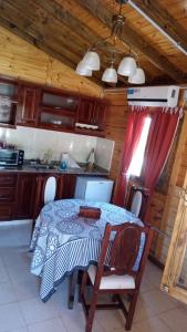 a kitchen with a table and a table and chairs at Cabaña El Refugio in La Carrera