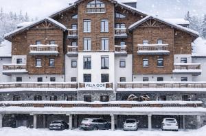 a large building with cars parked in the snow at Апартаменти Вілла Гор in Bukovel