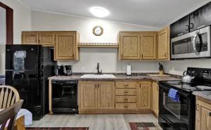a kitchen with wooden cabinets and a black refrigerator at Beach Bum Cabin in Florence
