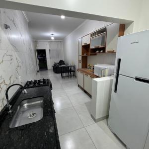 a kitchen with a white refrigerator and a stove at Apto Cozi in Sorriso
