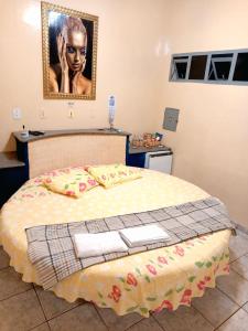a bedroom with a bed with a picture on the wall at Hostel Hotel uma otima opçao para suas ferias e um bom descanso in Cianorte