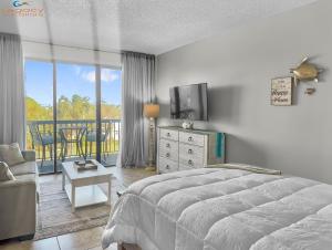 a bedroom with a bed and a tv and a balcony at Pirates Bay B303 in Fort Walton Beach