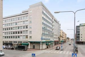 a large building on a city street with cars on the street at Helmi Pori Centrum in Pori