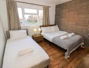 two beds in a room with a window and two candles at Leamington Spa House with 4 Bedrooms in Leamington Spa