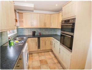 a kitchen with wooden cabinets and black counter tops at Leamington Spa House with 4 Bedrooms in Leamington Spa