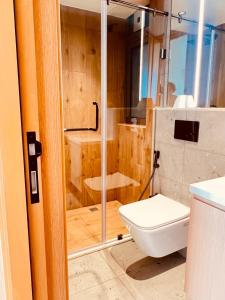 a bathroom with a toilet and a glass shower at RARA HM Suites in Hulhumale