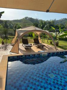 a tent and two chairs next to a pool at Luxury Capsule Haus Phuket in Panwa Beach