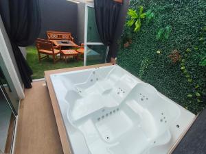 a white bath tub sitting next to a green hedge at Refugio Vem Viver in Mairiporã
