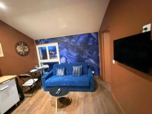 a living room with a blue couch and a tv at Le Saphir avec Parking gratuit in Montigny-le-Bretonneux