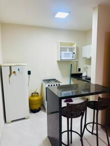 a kitchen with a counter with two chairs and a refrigerator at Bigorú Flats in Itacaré