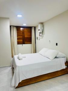 a bedroom with a large bed with white sheets and a window at Bigorú Flats in Itacaré
