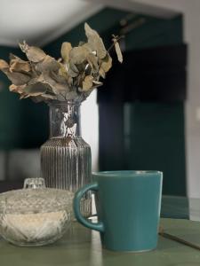 a blue coffee cup and a vase with a flower at Tandem - Espacio para dos - Cama King - Parking in Maipú