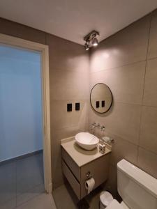 a bathroom with a sink and a toilet and a mirror at Edificio Domum Urquiza 134 in San Juan
