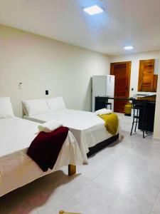two beds in a room with a kitchen in the background at Bigorú Flats in Itacaré +4 photos