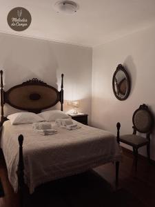 a bedroom with a bed and a mirror and a chair at Melodia do Campo in Terras de Bouro