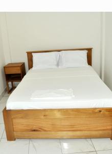 a bed with a wooden frame and white sheets at Résidence PAYAN in Douala